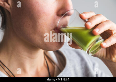 Donna verde bere il succo di wheatgrass shot Foto Stock