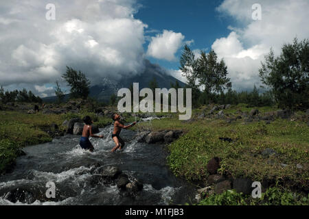 26 gennaio 2018 - Cagsawa, Albay, regione di Bicol, Filippine - i bambini godono di acqua in un fiume vicino al vulcano Mayon..Il vulcano Mayon eruzione ha realizzato decine di migliaia di residenti locali di dover lasciare la loro casa per rimanere nel governo fornito rifugi temporanei. L'ultima grande eruzione del vulcano Mayon è stato registrato nel 2013. (Credito Immagine: © Romeo Mariano/SOPA via ZUMA filo) Foto Stock