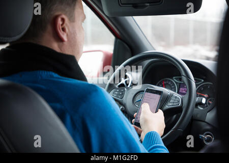 Praga, Repubblica Ceca - 21.01.1018: l'uomo utilizzando smart phone in auto durante la guida Foto Stock