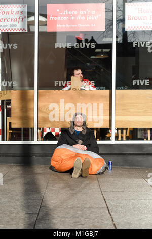 Uomo senza tetto al di fuori di un ristorante fast food in Nottingham, UK. Foto Stock