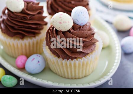 Pasqua tortini alla vaniglia con glassa di cioccolato e dolciumi e uova Foto Stock