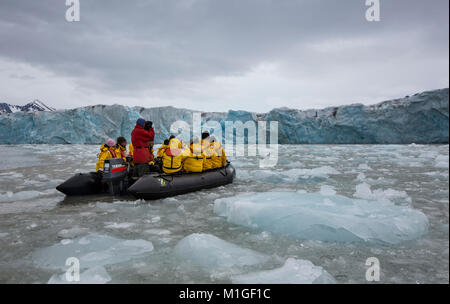 Svalbard, Norvegia, Luglio 7th, 2013: persone che viaggiano in un zodiac vicino imponente ghiacciaio Monaco Foto Stock