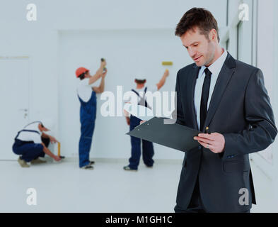 Giovane proprietario controlla i documenti in background di forza lavoro. Foto Stock