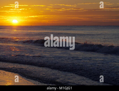 Alba sulle onde che si infrangono sulla spiaggia Foto Stock