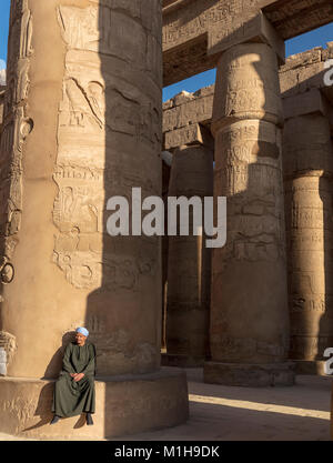 Placcato Djellabah guard si siede su una base a colonna in hypostyle hall del Tempio di Karnak Luxor Egitto Foto Stock