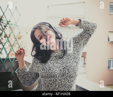 Happy girl dancing outdoor canto e ascolto di musica con cuffie background urbano Foto Stock