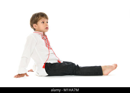 Little Boy in ucraino camicia ricamata a sedersi su sfondo bianco Foto Stock