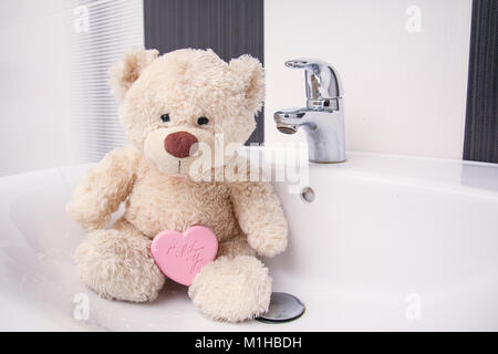 Un simpatico orsacchiotto è seduta nel bacino. Foto Stock