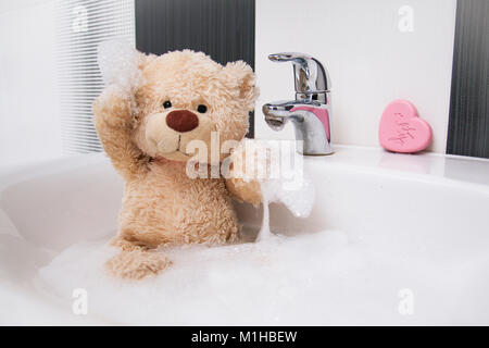 Un simpatico orsacchiotto è seduta nel bacino e lavaggio. Foto Stock