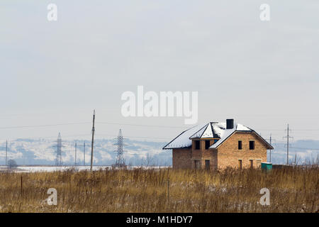 Moderno privato casa a due piani in costruzione senza una recinzione in un campo in inverno. Foto Stock