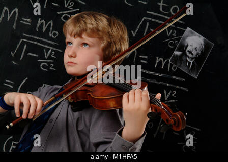 Un giovane maschio studente della scuola che è un abile Violin Player e matematico, visto di fronte a una lavagna, equasion e Albert Einstein foto Foto Stock