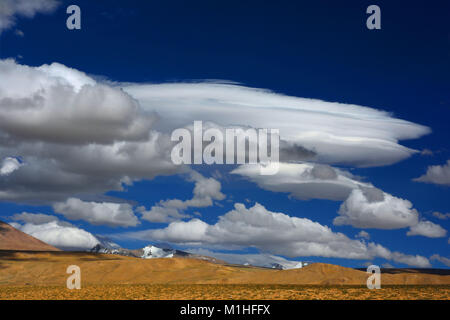 Alte montagne del deserto in autunno, giallo colline, picchi con neve sulle cime, cielo blu con bianco luminoso cumulus nubi, Himalaya. Foto Stock