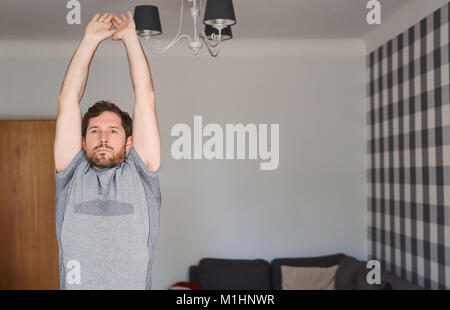 Montare il giovane uomo abbigliamento sportivo in esercizio a casa Foto Stock