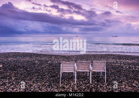 Sedie vuote sulla spiaggia in Larnaca nella calda luce di sunrise. Foto Stock