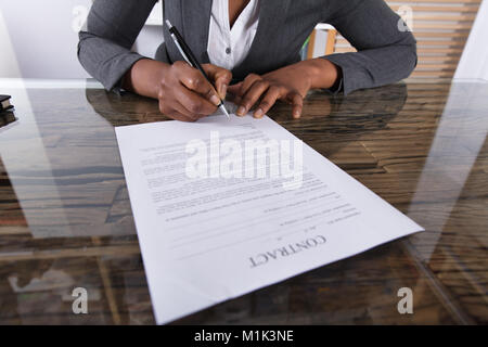 Close-up di imprenditrice tenendo la penna per firmare il contratto cartaceo Foto Stock