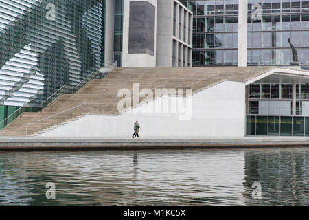 Giovane a piedi lungo il fiume Spree circondata dalla moderna architettura del quartiere governativo nella capitale tedesca Berlino Foto Stock