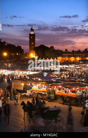 Il Marocco Marrakech, Piazza Djemaa El Fna, crepuscolo, cibo e bancarelle di frutta. Sullo sfondo la moschea di Koutoubia. Medina di Marrakesh. Unesco - Sito Patrimonio dell'umanità. Foto Stock