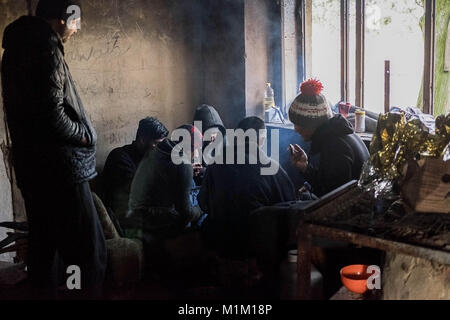 Kelebija, Serbia. 25 gennaio, 2018. In un'azienda abbandonata la casa vicino il confine Ungherese un gruppo di Pakistani i migranti stessi a caldo da un incendio. Ungheria e Croazia sono stati a rafforzare i controlli di frontiera negli ultimi anni che ha portato in molti rifugiati e migranti inceppato in Serbia. Credito: Edward Crawford/SOPA/ZUMA filo/Alamy Live News Foto Stock