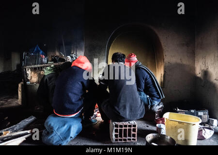 Kelebija, Serbia. 25 gennaio, 2018. In un'azienda abbandonata albergo vicino alla frontiera ungherese i migranti dal Pakistan scaldarsi accanto un incendio.Ungheria e Croazia sono stati a rafforzare i controlli di frontiera negli ultimi anni che ha portato in molti rifugiati e migranti inceppato in Serbia. Credito: Edward Crawford/SOPA/ZUMA filo/Alamy Live News Foto Stock