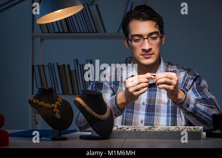 Giovane maschio gioielliere lavorando di notte nel suo laboratorio Foto Stock