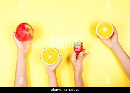 Cibo sano concetto. Molti ragazzi mani con fuits su sfondo giallo Foto Stock