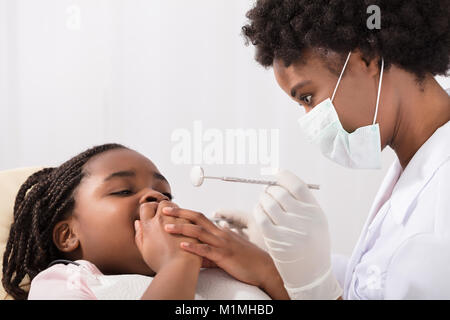 Spaventata ragazza che copre la bocca con le mani al dentista Foto Stock