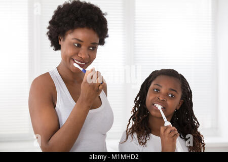 Madre africana e figlia lavarsi i denti in bagno Foto Stock