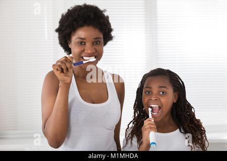 Madre africana e figlia lavarsi i denti in bagno Foto Stock