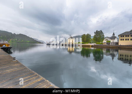 Pontile con traghetto passeggeri e la chiesa di Ulvik, Norvegia, Ulvikafjorden, Hordaland county, Hardangerfjord, riflessione nel fiordo Foto Stock