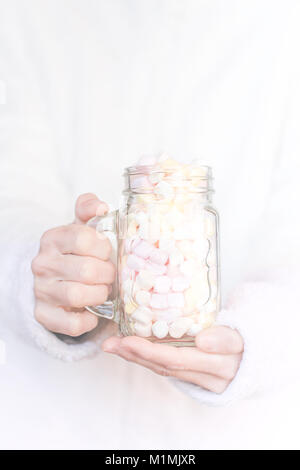 Donna che mantiene un bicchiere riempito con marshmallow Foto Stock