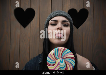 Ritratto di una donna con un lecca-lecca sporgenti dalla sua lingua Foto Stock