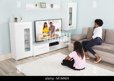 Madre e figlia che guarda godendo di guardare la televisione a casa Foto Stock