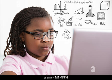 Close-up di una giovane ragazza africana utilizzando laptop con disegno educativo su sfondo bianco Foto Stock