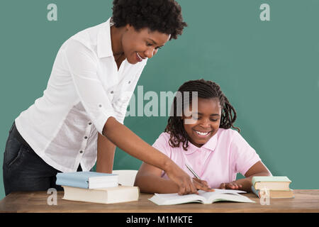Felice africana insegnante femminile aiutando il suo studente in compiti in classe Foto Stock