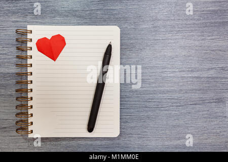 Blocco note con cuori rossi e una penna giaceva su un tavolo. Blocco note con il cuore. Foto Stock