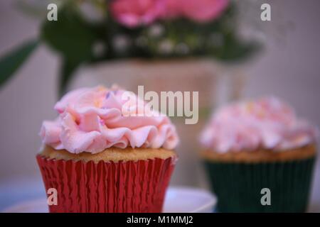 Artigianale di fragola deliziosa crema di burro rosa cupcake pane appena sfornato e con uno sfondo floreale Foto Stock