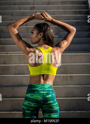 Giovane americano africano Stretching schiena indossando athleisure usura durante l ora d'oro in California. Foto di Francesco Specker Foto Stock