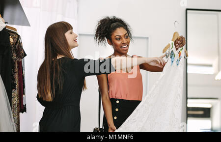 Il cliente avente un occhiata a un abito in una boutique. Donna imprenditore mostra abiti firmati a un cliente. Foto Stock