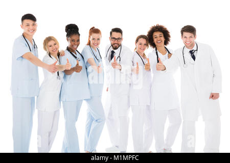 Gruppo del Team Medico gesticolando pollice in alto su sfondo bianco Foto Stock