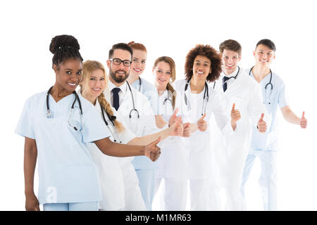 Sorridente Team Medico in piedi in fila gesticolando pollice in alto Foto Stock