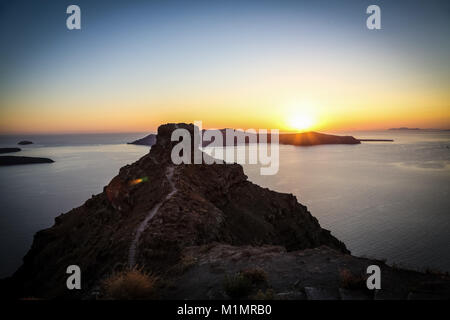 Skaros rock e Thirasia presso lo sfondo con il sole che tramonta, Santorini Island, Grecia Foto Stock