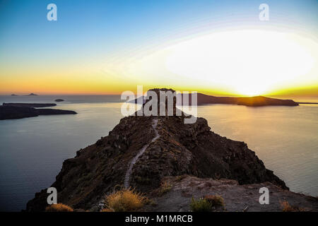 Skaros rock e Thirasia presso lo sfondo con il sole che tramonta, Santorini Island, Grecia Foto Stock