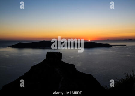 Skaros rock e Thirasia presso lo sfondo con il sole che tramonta, Santorini Island, Grecia Foto Stock