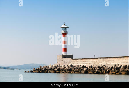 A strisce rosse e bianche torre faro sorge sul molo di entrata nel porto di Burgas, il litorale del Mar Nero, Bulgaria Foto Stock