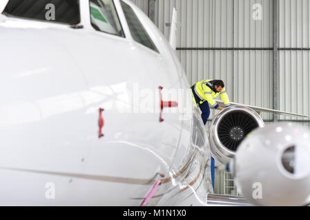 Il personale di terra dell'aeroporto controlla la tecnologia e la sicurezza di un getto in hangar Foto Stock