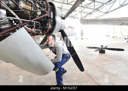 Meccanico aeronautico ripara un motore aeronautico in un hangar aeroporto Foto Stock