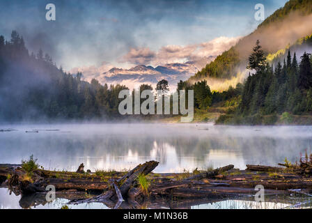 Bear Lake, nebbia di sunrise, inglese Pk e Mt Denver in dist, Selkirk Mtns, Zincton dividere zona, vicino Retallack città fantasma, British Columbia, Canada Foto Stock