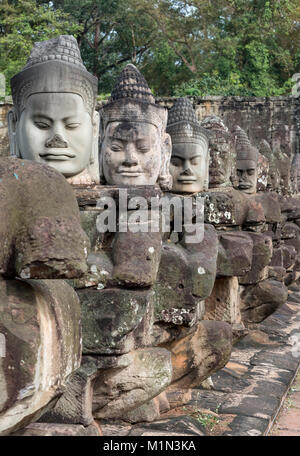 Facce di dio statue in pietra causeway davanti alla porta sud di Angkor Thom, Cambogia Foto Stock