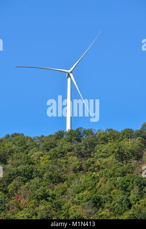 Gigante turbina a vento sulla collina contro il cielo blu Foto Stock