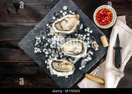 Foto aerea di ostriche con salsa vinaigrette e coltello Foto Stock